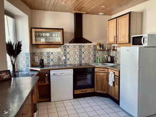 a kitchen with a white refrigerator and wooden cabinets at Le Nordmann - au coeur de Gérardmer in Gérardmer