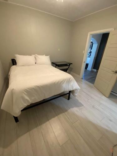 a bedroom with a white bed and a wooden floor at Le Convivial in Rouyn