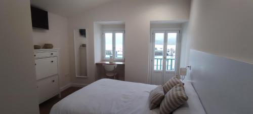 a white bedroom with a bed and a sink at El balcón de Carmen in O Barqueiro