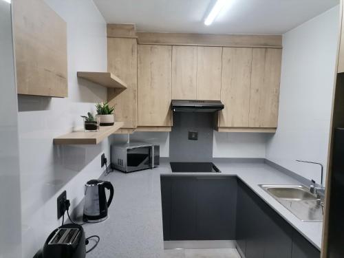 una pequeña cocina con armarios de madera y fregadero en Unit 802 Ten South en Durban