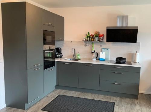 a large kitchen with gray cabinets and a sink at Lemke-Ferienwohnung in Nordhorn