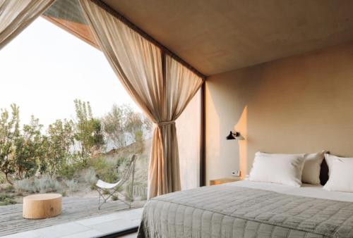 a bedroom with a bed and a large window at Pa.te.os in Melides