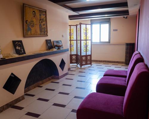 a waiting room with purple chairs and a fireplace at Madaba Hotel in Madaba