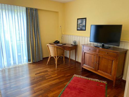 sala de estar con escritorio y TV de pantalla plana en Hotel Goldener Stern, en Sankt Ingbert