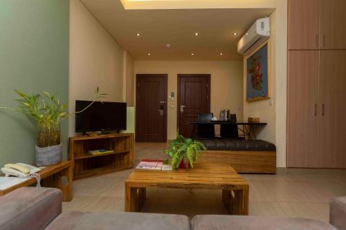 a living room with a couch and a tv at Roots Hotel Apartment in Accra