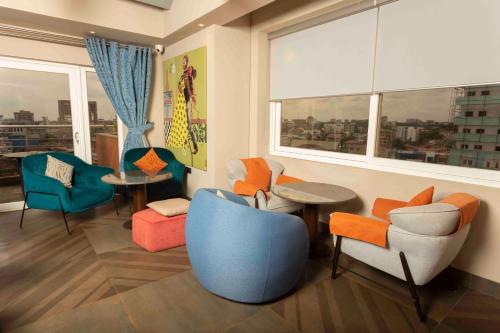 a living room with chairs and tables and a window at Roots Hotel Apartment in Accra