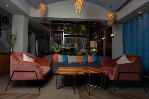 a living room with a couch and two chairs and a table at Roots Hotel Apartment in Accra