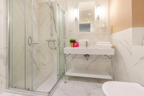 een witte badkamer met een douche en een wastafel bij VacationClub - Baltic Park Fort Apartament G.409 in Świnoujście