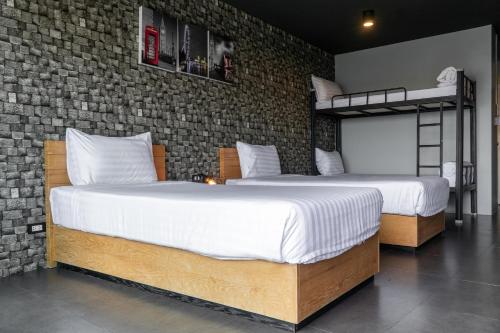 two beds in a bedroom with a brick wall at Get Zleep Premium Budget Hotel in Chiang Mai