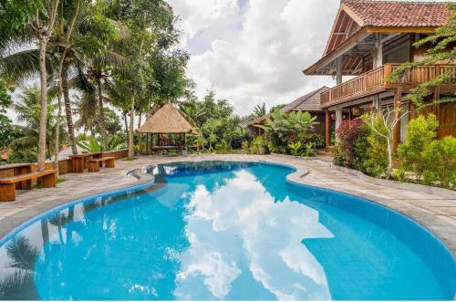 a swimming pool in front of a house at Peraja Bungalows Loyok in Sangyang