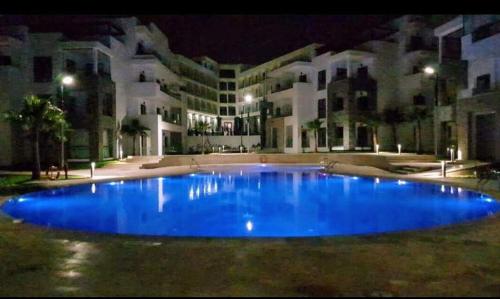 a large blue pool in front of a building at night at Hivernage Founty in Agadir
