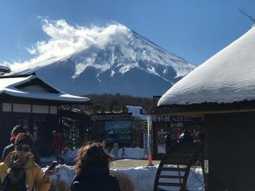 a snow covered mountain in the background with people standing around at 都心の家30 square meter king size bed, step meter, 3-person room201 in Tokyo