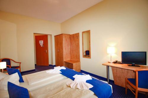 a hotel room with two beds and a desk and a television at Gasthaus Zum Schwan in Oschatz