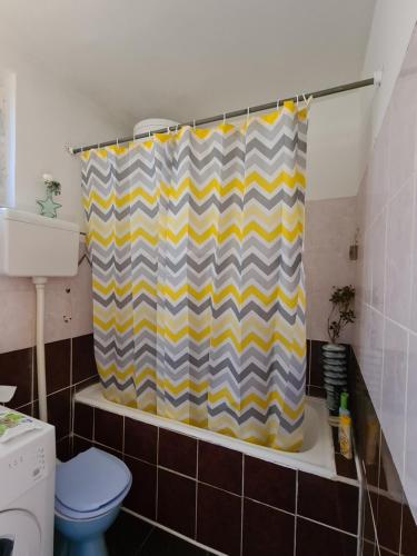 La salle de bains est pourvue d'un rideau de douche jaune et gris. dans l'établissement Garden Room, à Novi Sad