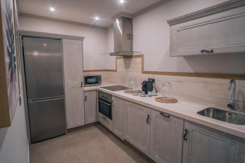a kitchen with wooden cabinets and a stainless steel refrigerator at Apartamentos Turísticos La Baílla in Rota