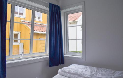 1 Schlafzimmer mit einem Bett und 2 Fenstern mit blauen Vorhängen in der Unterkunft Lovely Home In Tvedestrand With Wifi in Tvedestrand
