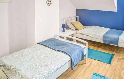 two beds in a room with blue walls and wooden floors at 2 Bedroom Awesome Home In Grzybowo in Grzybowo