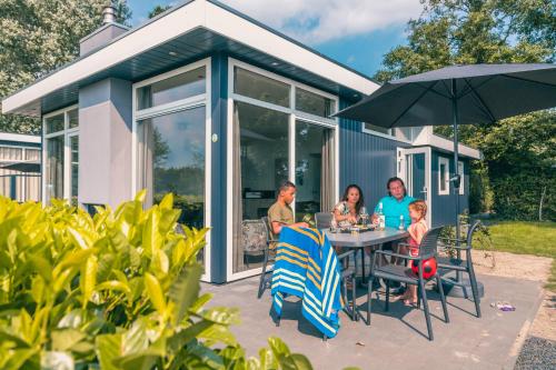 a family sitting at a table in front of a house at EuroParcs De Biesbosch in Willemsdorp