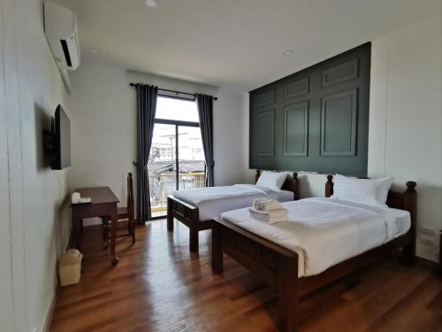 1 dormitorio con 2 camas y ventana en โรงแรมรชาโขง Racha Khong Hotel en Nakhon Phanom