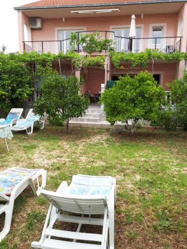a group of lounge chairs in front of a building at Apartman Laura in Kaštela