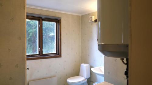 a bathroom with a toilet and a sink and a window at Little Forest House "Our Little Farm" in Ekshärad