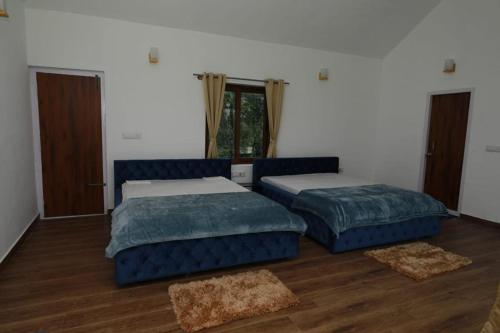two beds in a room with wooden floors at The Vale Of Arryn in Madikeri