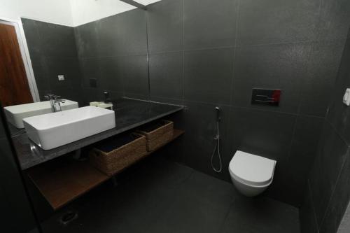 uma casa de banho com um lavatório branco e um WC. em The Vale Of Arryn em Madikeri