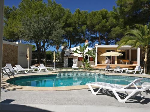 a swimming pool with lounge chairs and a house at Apartamentos Playa Calan Blanes in Cala en Blanes