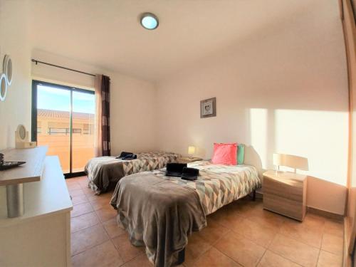 ポルティマンにあるParaíso Sol Rocha Ocean Beach Apartmentのベッド2台と窓が備わるホテルルームです。