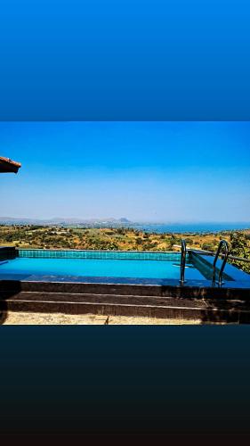 a blue swimming pool with a view of the desert at EZE NOF - A hilltop villa with 360º water view in Nashik