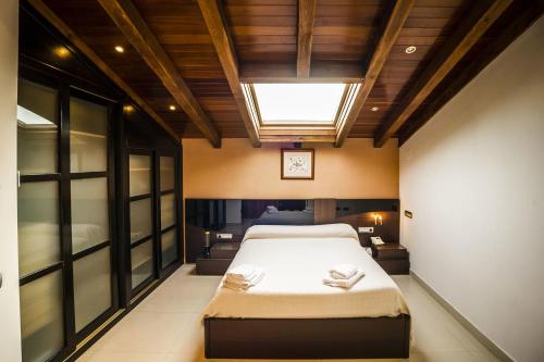 a bedroom with a large bed and a skylight at Casa Rural Spa La Chirumba in Aldeatejada