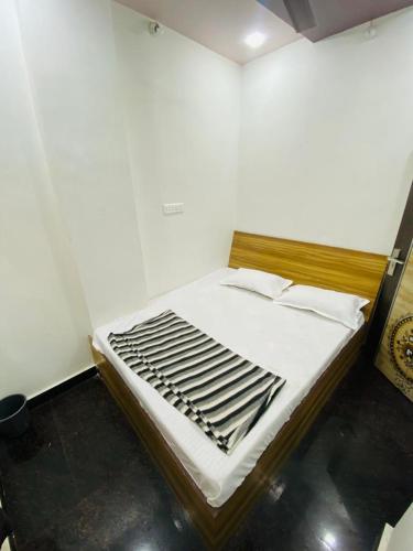 a bedroom with a bed with white sheets and wooden frame at Hotel Arsh Palace in Ajmer