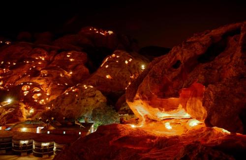 a group of rocks with lights at night at Little Petra Bedouin Camp in Al Ḩayy