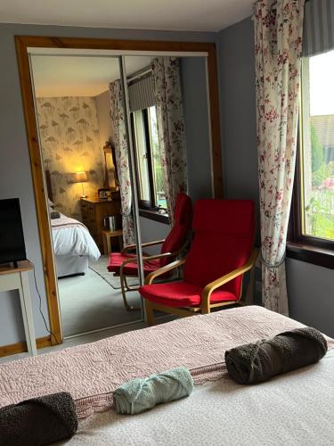 a bedroom with a red chair and a mirror at Black Isle View in Dingwall