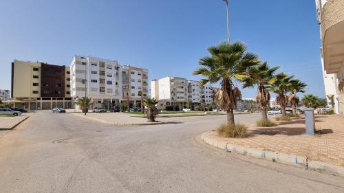 an empty street with palm trees and buildings at My Cosy Place Rabat - Cosy Home Wifak Temara in Temara
