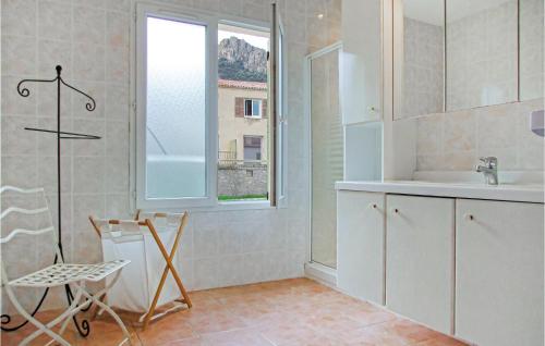 アルガジョラにあるCozy Home In Algajola With Kitchenのバスルーム(シンク、椅子付)、窓が備わります。