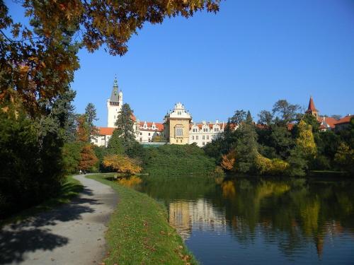 a large castle sitting on the side of a lake at Park Hotel Pruhonice in Pruhonice