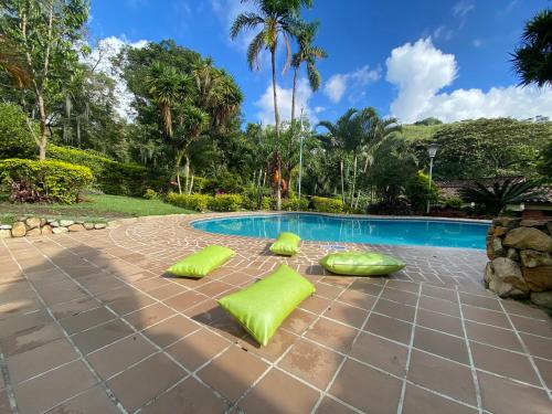 a patio with lime green cushions next to a swimming pool at Finca Villa Chalet Del Rio Cali Farm Villa Chalet Cali River in Cali