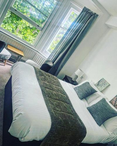 a bedroom with a large bed and two windows at The Beach Hotel in Minehead
