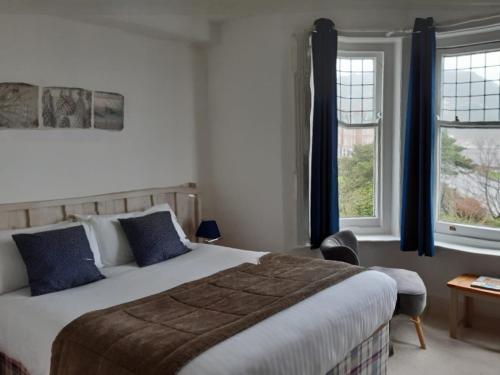a bedroom with a large bed and two windows at The Beach Hotel in Minehead
