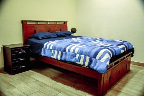 1 dormitorio con 1 cama con manta azul y blanca en Casa de Campo - Baños de Agua Santa, en Juivi
