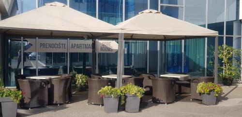 two tables and chairs under an umbrella in front of a building at Kristal Garni Hotel in Novi Sad