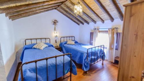 2 camas en un dormitorio con edredón azul en El Morrón Algarinejo by Ruralidays en Algarinejo