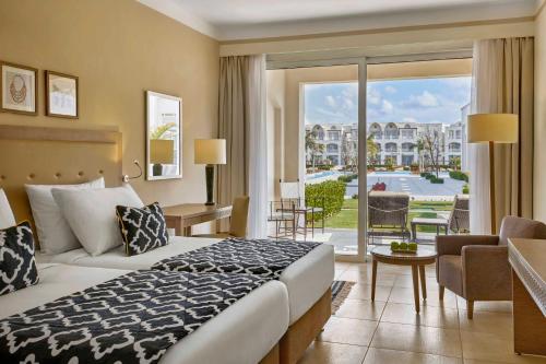 a hotel room with a bed and a large window at Steigenberger Resort Alaya Marsa Alam - Red Sea - Adults Friendly 16 Years Plus in Coraya Bay