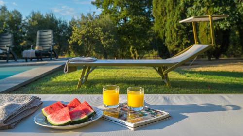 a table with two glasses of orange juice and watermelon at CASALE DELL'OASI 12, Emma Villas in Gallese