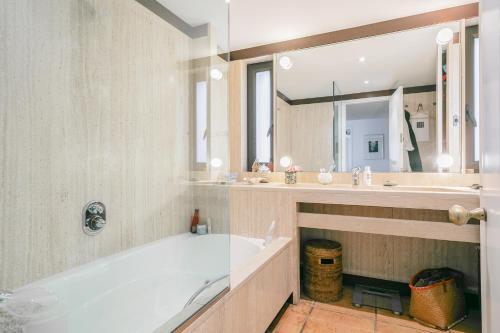 ein Badezimmer mit einer Badewanne, einem Waschbecken und einem Spiegel in der Unterkunft Punta d'en Bailet in Cadaqués
