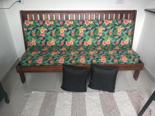 a bench with a flower pattern on it with two pillows at Apts centro Ubatuba in Ubatuba