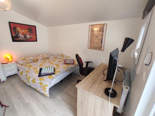 a bedroom with a bed and a desk with a computer at Chalet Aurore in Mérignac