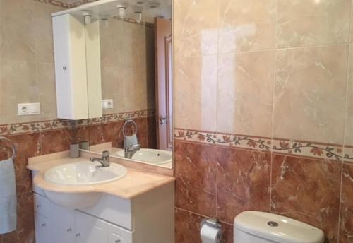 Un baño con lavabo, inodoro y espejo. en Cozy bright apartment, en Guardamar del Segura