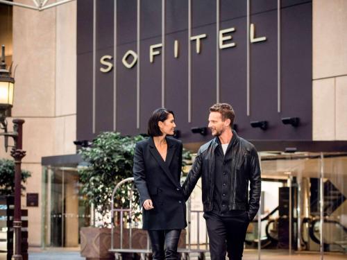 a man and a woman walking in front of a building at Sofitel Melbourne On Collins in Melbourne